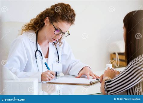 Female Doctor Prescribing Medication For Patient In The Office Stock
