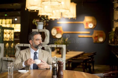 Thoughtful Handsome Mature Businessman Drinking Coffee In Cafe Stock
