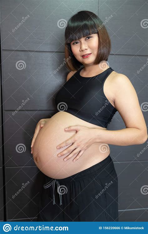 Pregnant Asian Woman Touching Her Big Belly Happily Stock