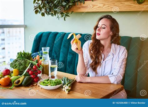 Belle Jeune Femme Mangeant De La Banane Assise Dans La Cuisine Photo Stock Image Du Sain