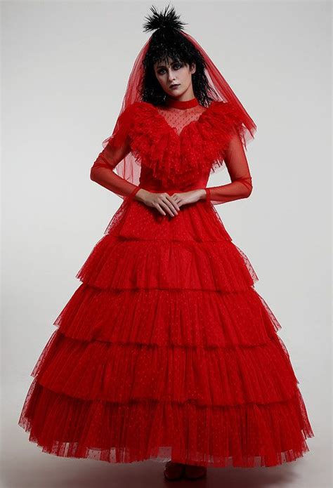 a woman in a red dress and veil is standing on a white surface with her hands on her hips