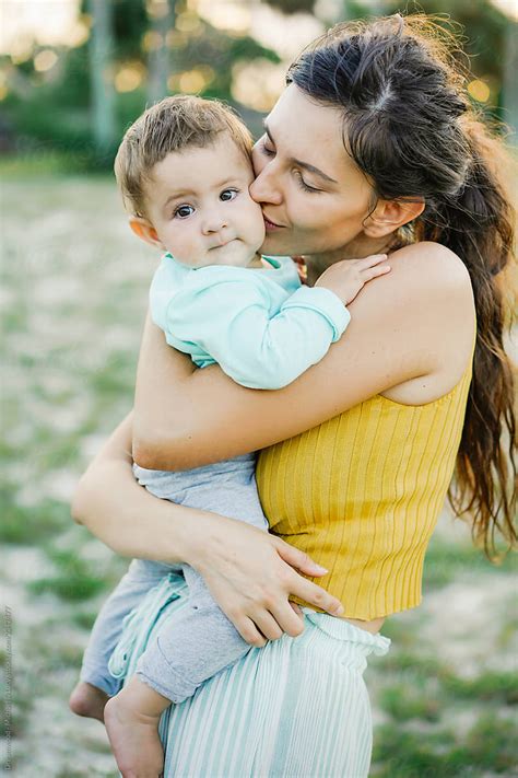 Young Mother Hugging And Kissing Son In Park By Dreamwood Photography