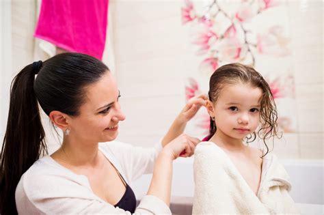 Beautiful Young Mother Combing Hair Of Her Little Daughter After Taking