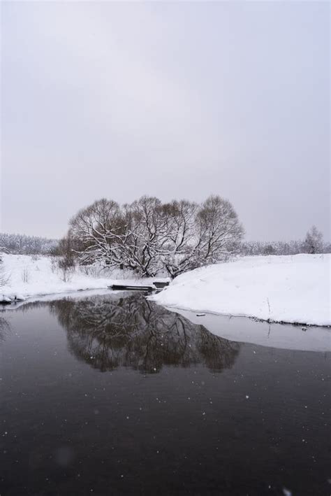 Serene Winter Landscape Dark River Grey Sky And Deep Snow On Banks