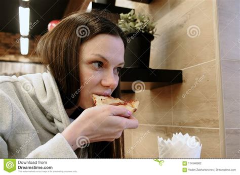Brunette Young Hungry Woman Bites Off A Tasty Slice Of Pizza And Eat It