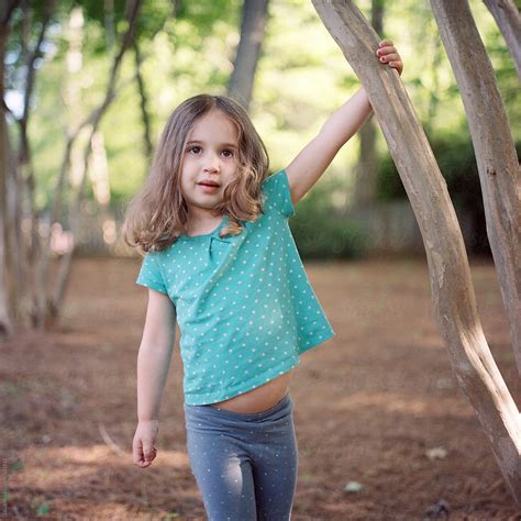 Beautiful Young Girl Holding On To A Tree Branch Outside By Stocksy