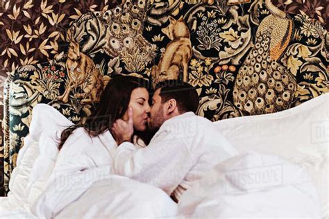 Couple Kissing While Lying On Bed In Hotel Room Stock Photo Dissolve