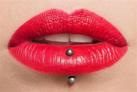 A Womans Lips With Red Lipstick And Black Balls On The Bottom Of Her Lip