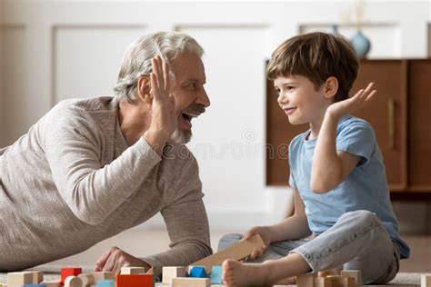 Overjoyed Mature Grandfather Playing With Adorable Grandson At Home