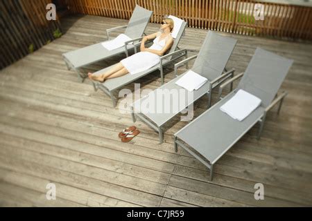 Woman Sunbathing In Lawn Chair With Boy And Girl Playing In Yard Stock