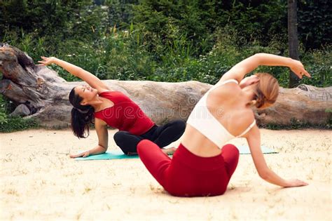 two girls do yoga in the park on the sand among the trees international couple of girls doing