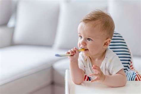 Premium Photo Cheerful Baby Child Eats Food Itself With Spoon