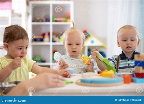Group Of Babies Is Playing At Table In Nursery Or Creche Toddlers In