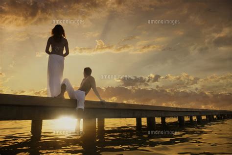 Caucasian Couple Admiring Sunset From Dock Over Ocean 11018055757 の写真素材