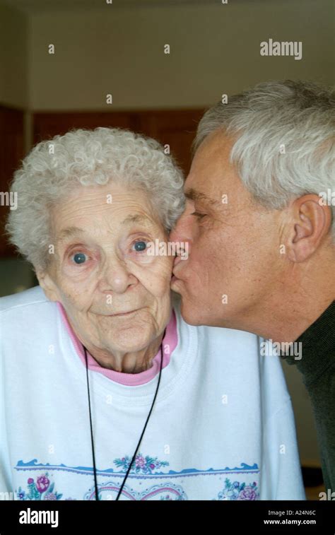 60 Year Old Senior Male Kisses Mother On The Cheek On Her 85 Birthday