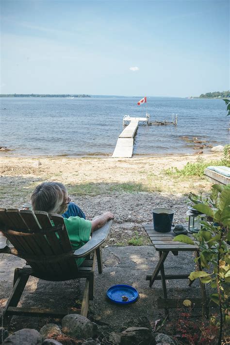 Senior Woman Relaxing By Lake Beach By Stocksy Contributor Joselito