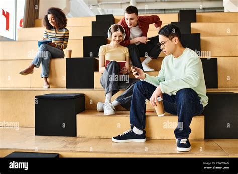 Multicultural students sit and chat on a set of indoor stairs