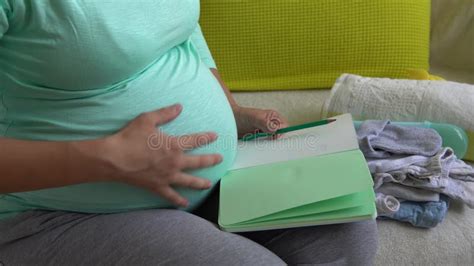 Cute Pregnant Woman Writing Packing List For Maternity Hospital With