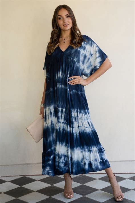 A Woman Standing In Front Of A Wall Wearing A Blue And White Tie Dye Dress