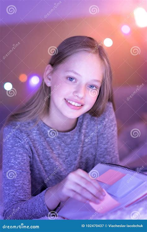 muchacha de ojos azules que sonríe y que sostiene su cuaderno imagen de archivo imagen de