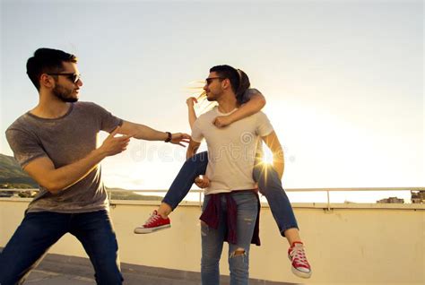 Group Of Young People Having Fun At A Rooftop On Sunset Stock Photo