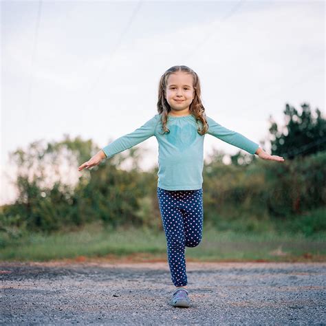 Cute Young Girl Standing On One Leg Outside By Stocksy Contributor