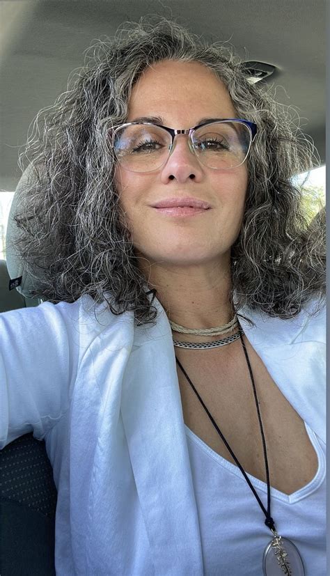 A Woman Wearing Glasses And A White Shirt Is Sitting In The Back Seat
