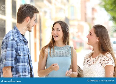 Three Friends Talking Taking A Conversation On The Street Stock Photo