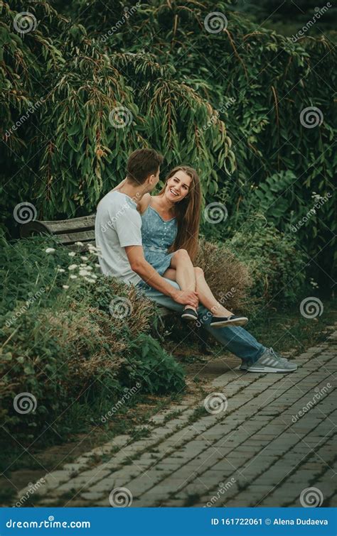 Beautiful Couple In Love Sits In A Park On A Bench In The Summer And