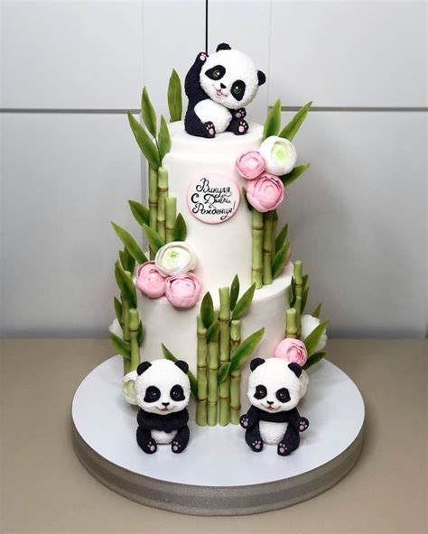 A Three Tiered Cake Decorated With Panda Bears And Bamboo Leaves On A