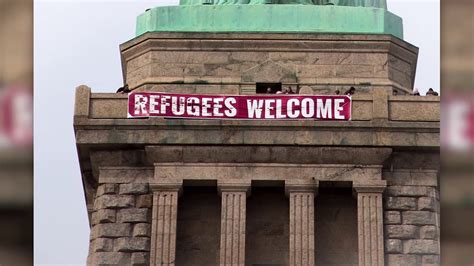 ‘refugees welcome banner unfurled at statue of liberty