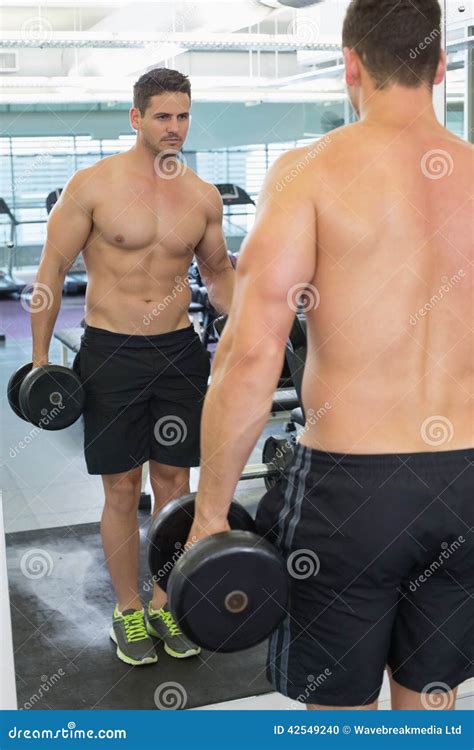 Shirtless Bodybuilder Lifting Heavy Black Dumbbell Looking In Mirror