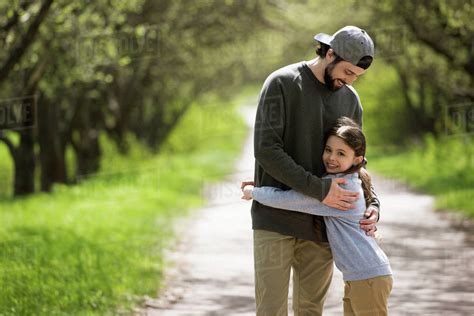 Father Embracing Daughter On Path In Park Stock Photo Dissolve