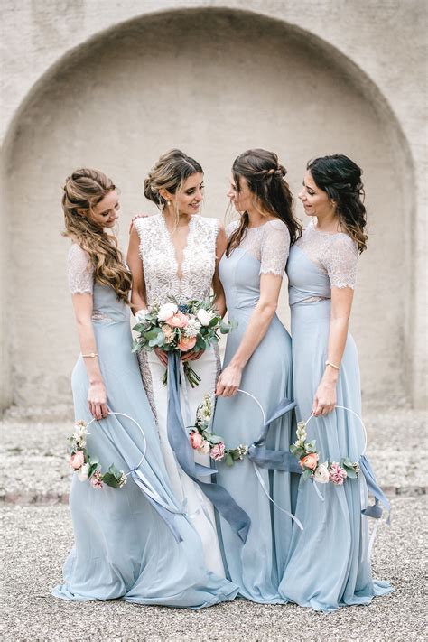 Three Bridesmaids In Long Blue Dresses With Flowers And Ribbons On