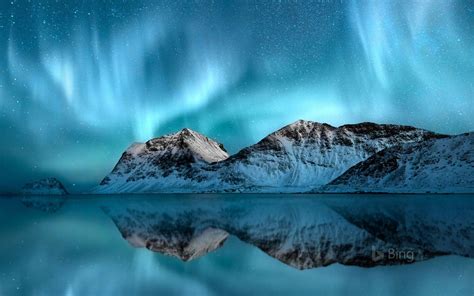 The Northern Lights Shine Brightly Over Snow Covered Mountains And