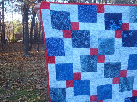 A Blue And Red Quilt Is Hanging On A Clothes Line In Front Of Some Trees
