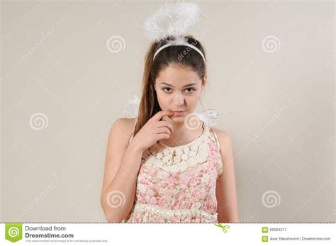 Πορτρέτο του χαριτωμένου πολύ ντροπαλού κοριτσιού αγγέλου με το δάχτυλο κοντά στο στόμα της Στοκ