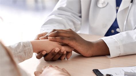 A Doctors Hands Hold A Patients From Across A Table