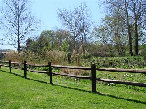 A tamping bar is used to compact the dirt around the post while backfilling. Various Rail Fences - Expert Fence in Alexandria Virginia