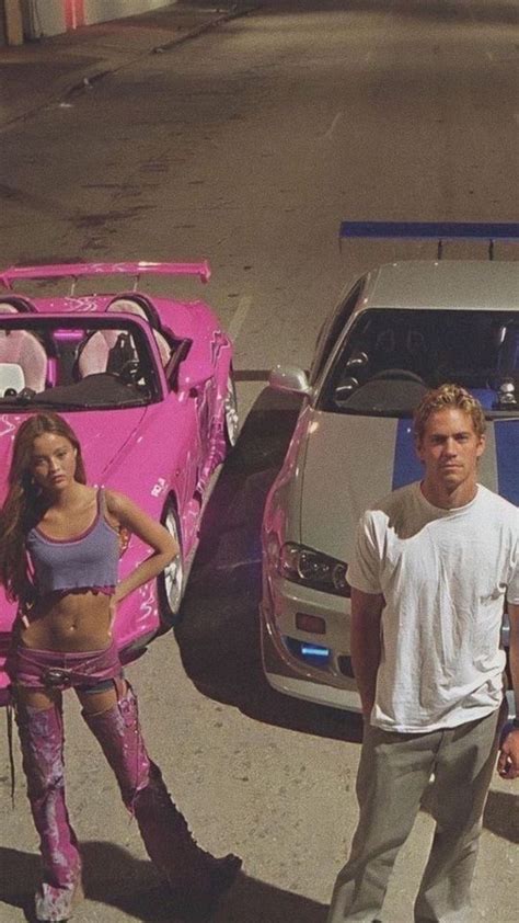 Two People Standing In Front Of Cars With Pink Paint On Them And One