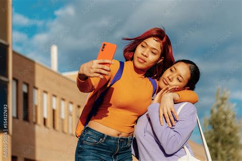 Two Latina Girls Sisters And Friends Taking A Picture With A Smartphone At The Exit Of The