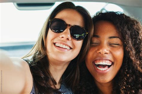 happy multiethnic female friends taking a selfie inside a car by stocksy contributor