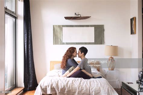 Side View Of Romantic Lesbians Rubbing Noses While Sitting On Bed Photo