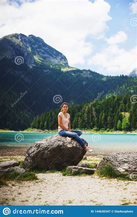 Tourist Girl Enjoys The Magical View Sitting On Big Stone On The Shore