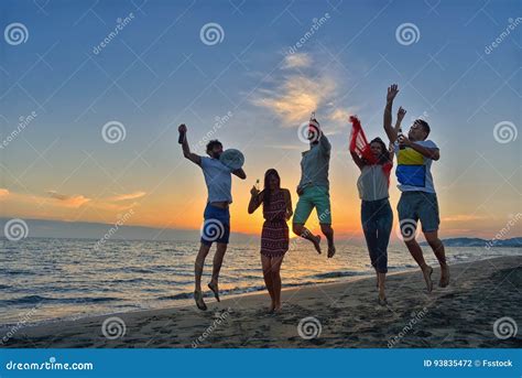 Group Of Happy Young People Is Running On Background Of Sunset Beach