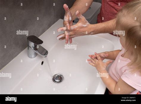 El padre le muestra a su hijo cómo lavarse las manos correctamente
