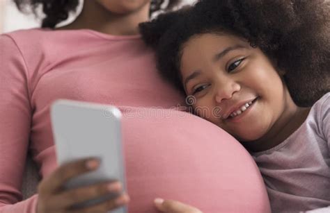 pregnant black woman and her little daughter using smartphone at home stock image image of