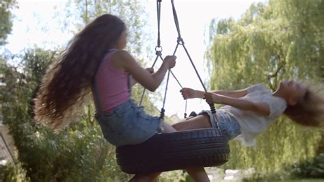 Two Girls Playing On Tire Swing In Garden Stock Video Footage Storyblocks