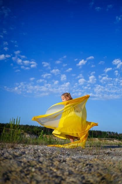 Linda loira linda encaracolada com um vestido amarelo de verão na natureza Foto Premium