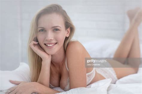 Portrait Of Young Woman Lying On Bed Wearing Underwear High Res Stock